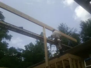 Carpenter setting a ridge beam over a new addition frame — Ice Dam Removal by Roofing Brothers in Belfield