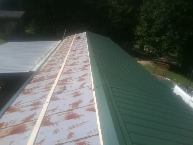 Old rusted panels beside newly installed green metal roofing — Wind Damage Roof Repair by Roofing Brothers in Belfield