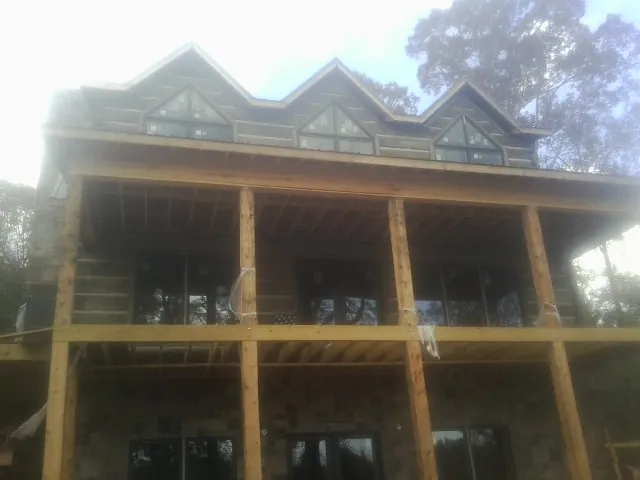 Dormers and porch framing on a large log home under construction — Roof Coating work by our crew in Belfield