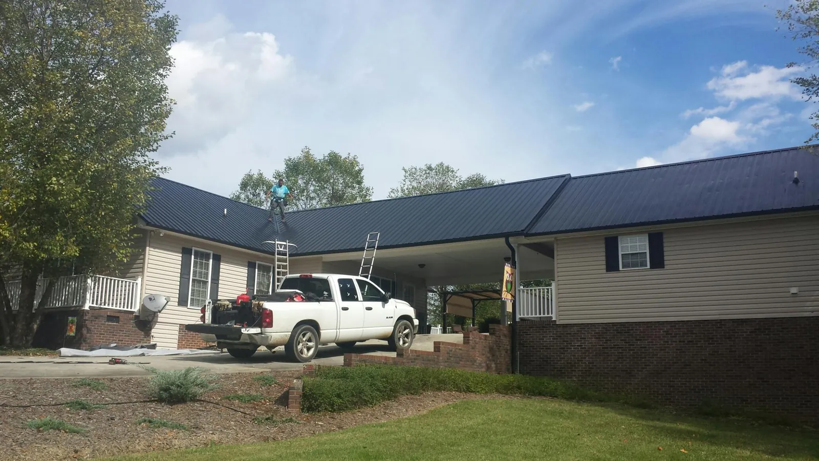 Black metal roof over a home and attached breezeway with ladders set in Belfield
