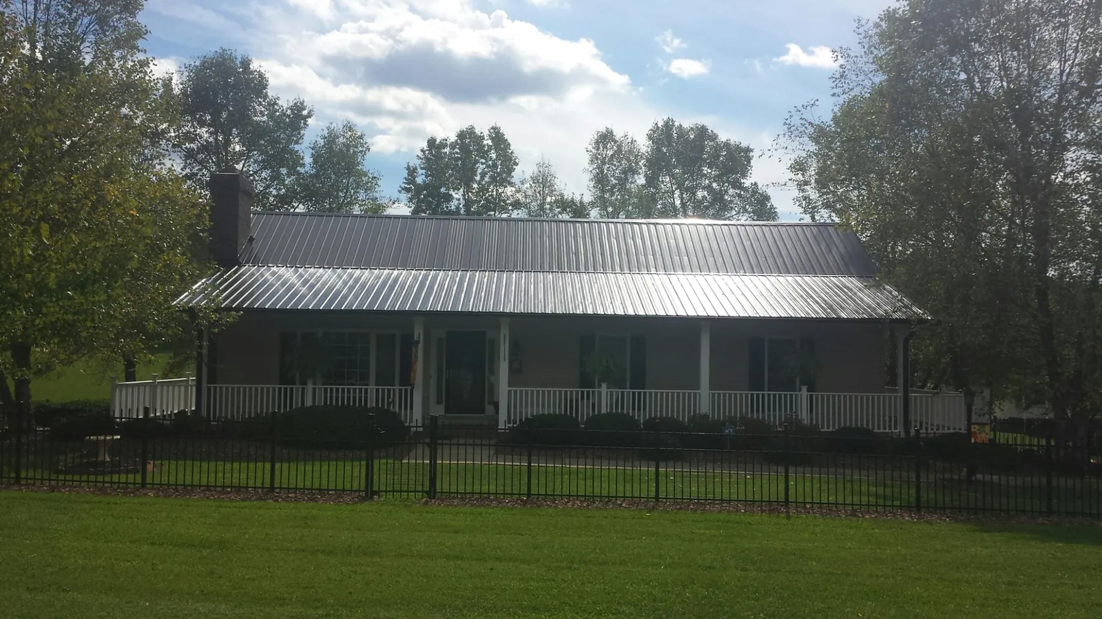 Gray metal roof on a brick ranch with a full width front porch — Gutter Guard Installation work by our crew in Belfield