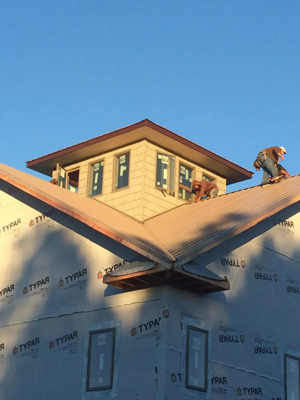 Roofers working around a rooftop cupola on a new metal roof at sunset — Roof Waterproofing in Belfield by Roofing Brothers